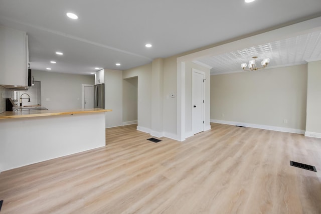 50 14th St, Bangor, ME 04401 - unfurnished living room featuring light wood finished floors, baseboards, a sink, a chandelier, and recessed lighting