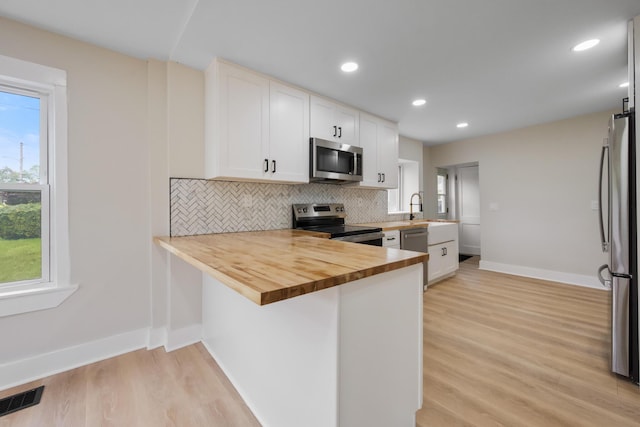 50 14th St, Bangor, ME 04401 - kitchen featuring stainless steel appliances, baseboards, wooden counters, light wood-type flooring, and decorative backsplash