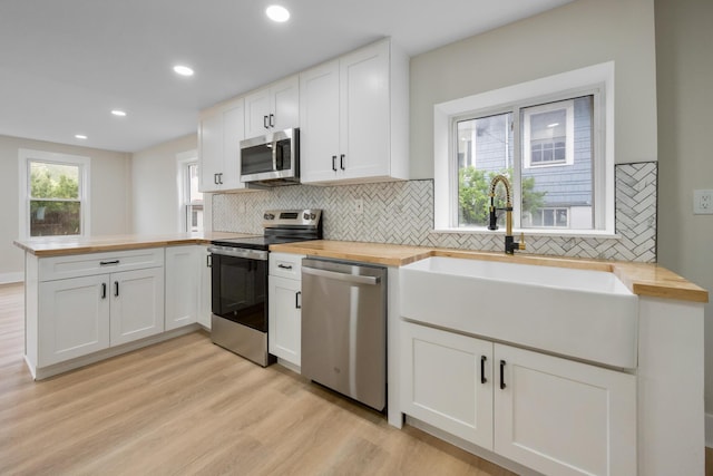 50 14th St, Bangor, ME 04401 - kitchen featuring appliances with stainless steel finishes, butcher block counters, a sink, a peninsula, and recessed lighting