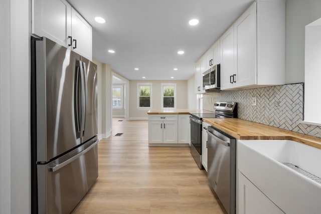 50 14th St, Bangor, ME 04401 - kitchen with stainless steel appliances, butcher block counters, white cabinets, backsplash, and light wood-style flooring