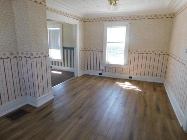 10 Summer St, Calais, ME 04619 - spare room featuring wallpapered walls, wood finished floors, baseboards, and crown molding