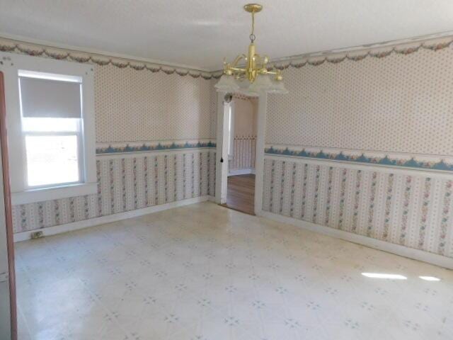 10 Summer St, Calais, ME 04619 - empty room with a chandelier, tile patterned floors, wallpapered walls, and baseboards
