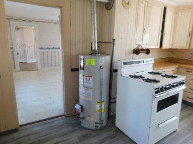 10 Summer St, Calais, ME 04619 - kitchen featuring white gas range, gas water heater, light brown cabinetry, wood finished floors, and light countertops