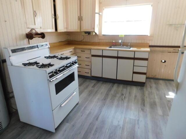 10 Summer St, Calais, ME 04619 - kitchen with white gas stove, light wood finished floors, light countertops, and a sink