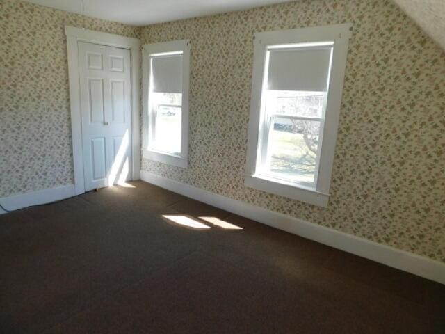 10 Summer St, Calais, ME 04619 - unfurnished room featuring wallpapered walls, plenty of natural light, dark colored carpet, and baseboards