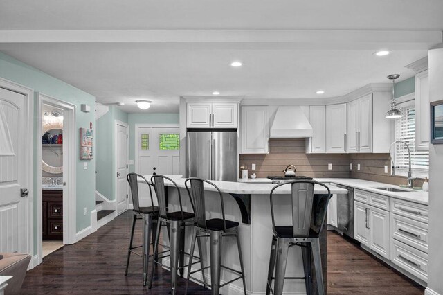 14 Winter Hills Ln, Ogunquit, ME 03907 - kitchen with appliances with stainless steel finishes, premium range hood, a breakfast bar area, a sink, and white cabinetry
