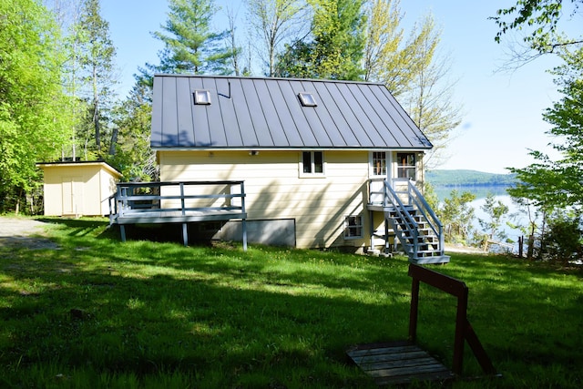 1809 Embden Pond Rd, Embden, ME 04958 - rear view of house featuring a standing seam roof, stairs, a deck with water view, a lawn, and metal roof