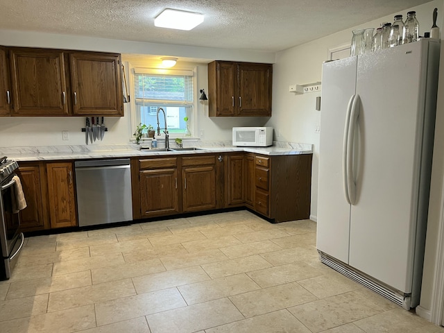 39 Thompson St, Wells, ME 04090 - kitchen with appliances with stainless steel finishes, light countertops, a textured ceiling, and light tile patterned flooring