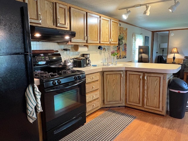 1236 Waldo Station Rd, Waldo, ME 04915 - kitchen with black appliances, under cabinet range hood, a peninsula, light countertops, and a sink