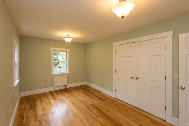 17 Spruce St, Rockport, ME 04856 - unfurnished bedroom with radiator heating unit, light wood-style flooring, baseboards, and a closet
