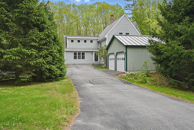 17 Lincoln Ln, Newcastle, ME 04553 - view of front of home featuring a standing seam roof, a garage, a chimney, metal roof, and an outbuilding