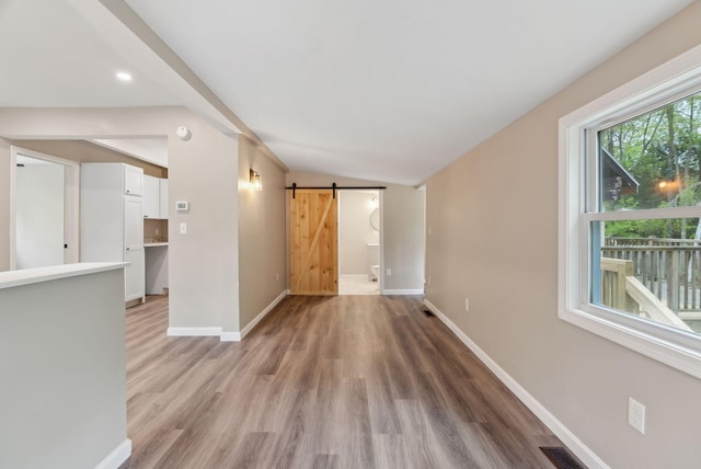 834-836 Sebago Rd, Sebago, ME 04029 - spare room with a barn door, baseboards, light wood-type flooring, vaulted ceiling, and recessed lighting
