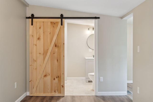 834-836 Sebago Rd, Sebago, ME 04029 - unfurnished bedroom with a barn door, wood finished floors, baseboards, and ensuite bathroom