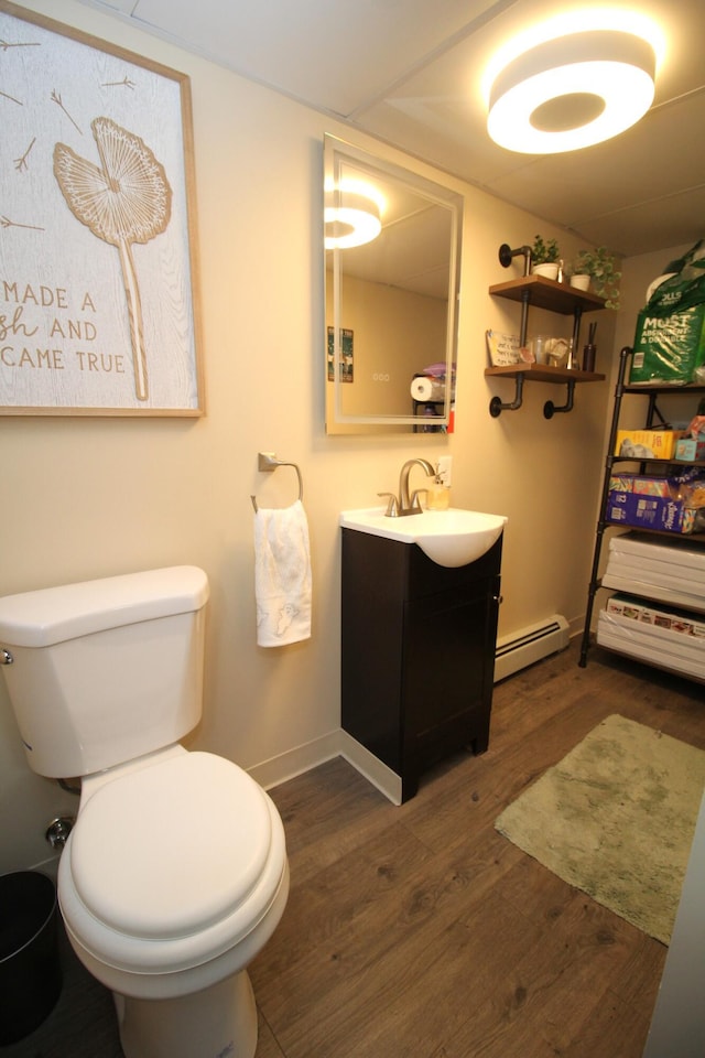24 Mitchell St, Lewiston, ME 04240 - bathroom with a baseboard heating unit, vanity, toilet, wood finished floors, and baseboards