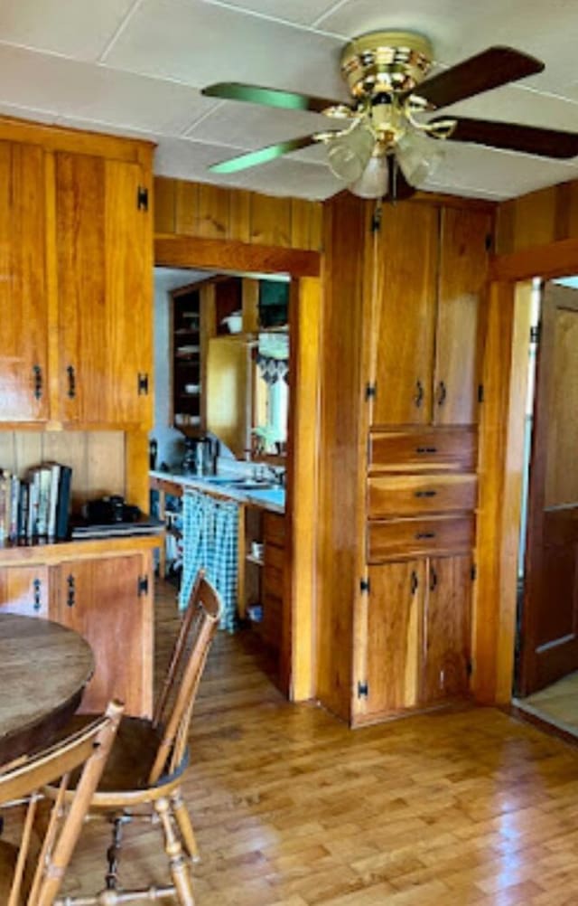 634 N Rd, Mount Chase, ME 04765 - kitchen featuring wood walls, brown cabinets, ceiling fan, and light wood-style flooring