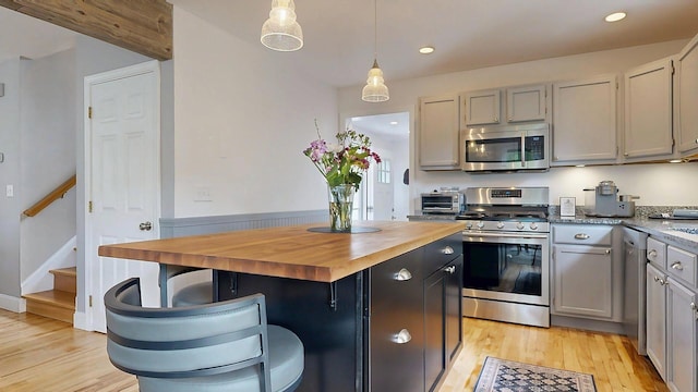 53 Gray Rd, Gorham, ME 04038 - kitchen with stainless steel appliances, butcher block countertops, light wood finished floors, decorative light fixtures, and a kitchen island