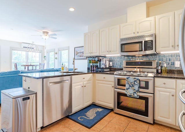 22 Cormorant Pl Unit 22, South Portland, ME 04106 - kitchen featuring appliances with stainless steel finishes, a sink, decorative backsplash, a ceiling fan, and a peninsula