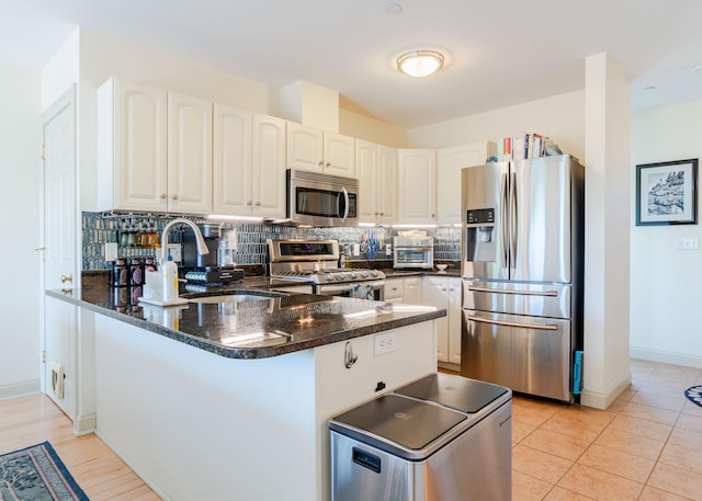 22 Cormorant Pl Unit 22, South Portland, ME 04106 - kitchen featuring stainless steel appliances, a peninsula, decorative backsplash, and white cabinetry