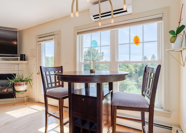 22 Cormorant Pl Unit 22, South Portland, ME 04106 - dining area with a wall mounted air conditioner, light wood-style flooring, a glass covered fireplace, and baseboard heating
