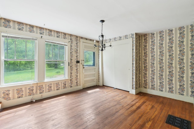 705707 Maine Ave, Farmingdale, ME 04344 - unfurnished dining area featuring wallpapered walls, a chandelier, and wood-type flooring