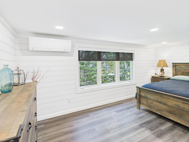 1107 S Shore Rd, Madawaska Lake Twp, ME 04783 - bedroom with a wall unit AC, wood finished floors, recessed lighting, wooden walls, and baseboards