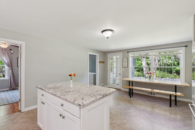 83 E Cote St, Lewiston, ME 04240 - kitchen featuring healthy amount of natural light, white cabinets, and baseboards