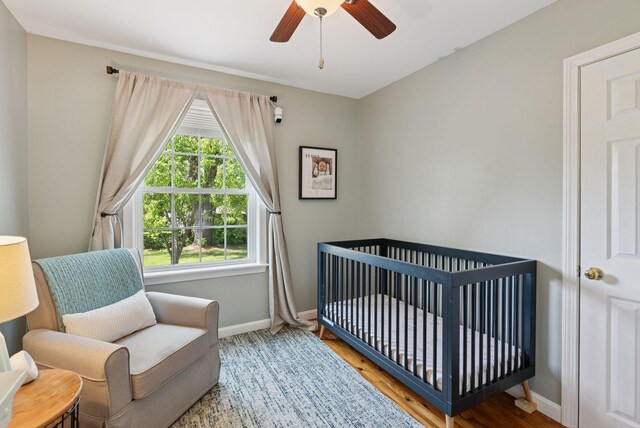 83 E Cote St, Lewiston, ME 04240 - bedroom featuring baseboards, a crib, wood finished floors, and a ceiling fan
