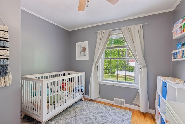 83 E Cote St, Lewiston, ME 04240 - bedroom with ornamental molding, a nursery area, wood finished floors, baseboards, and ceiling fan
