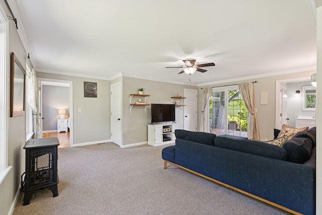 83 E Cote St, Lewiston, ME 04240 - living room featuring a wood stove, a ceiling fan, crown molding, carpet flooring, and baseboards