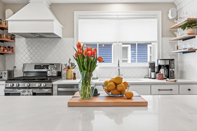 15 Pacer Way, Scarborough, ME 04074 - kitchen with open shelves, stainless steel range with gas stovetop, custom range hood, and backsplash