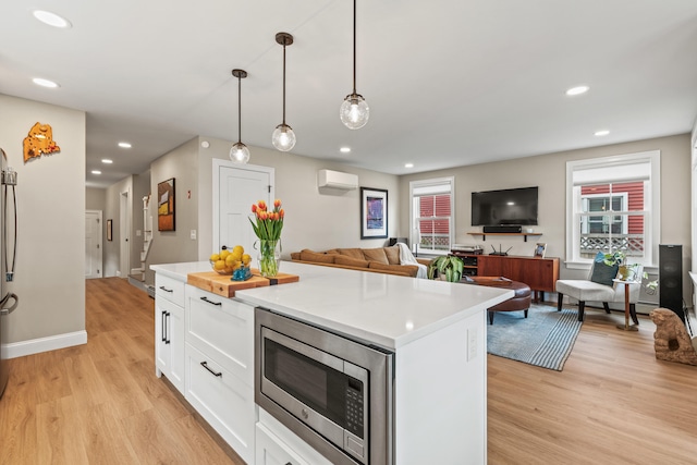15 Pacer Way, Scarborough, ME 04074 - kitchen with stainless steel microwave, a wall unit AC, light wood-style floors, white cabinets, and light countertops