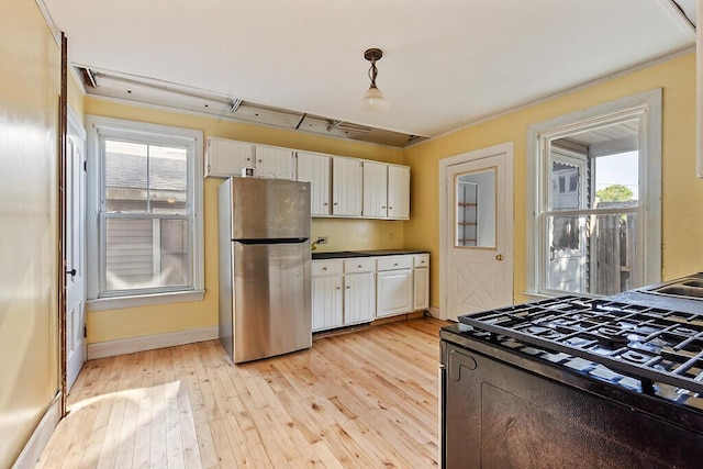 2 Elm Ter, Waterville, ME 04901 - kitchen featuring freestanding refrigerator, range with gas cooktop, light wood finished floors, white cabinets, and healthy amount of natural light