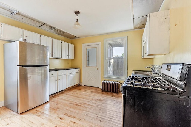 2 Elm Ter, Waterville, ME 04901 - kitchen featuring stainless steel appliances, a sink, radiator heating unit, light wood-type flooring, and white cabinets