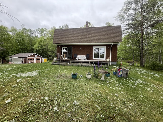 593 S Strong Rd, Strong, ME 04983 - view of front of house with a shingled roof, a detached garage, an outdoor structure, a front lawn, and a chimney