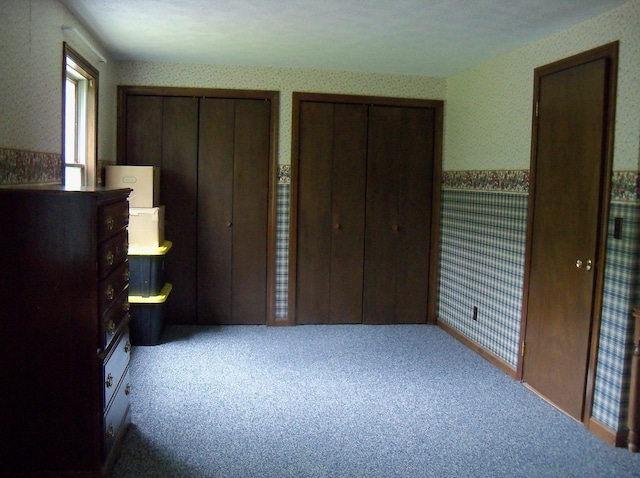 593 S Strong Rd, Strong, ME 04983 - unfurnished bedroom featuring wallpapered walls, a wainscoted wall, multiple closets, and carpet