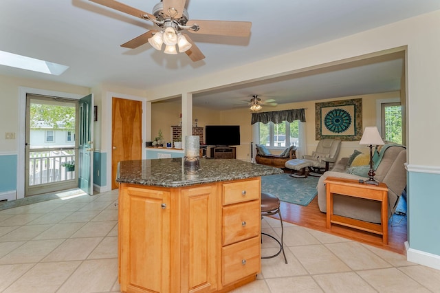 5 Nash Pkwy, Somersworth, NH 03878 - kitchen with a kitchen island, a ceiling fan, light tile patterned flooring, dark stone counters, and a kitchen breakfast bar