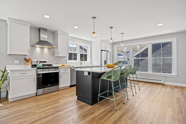 4 Frontrunner Way, Scarborough, ME 04074 - kitchen featuring wall chimney exhaust hood, appliances with stainless steel finishes, baseboard heating, a kitchen breakfast bar, and light wood-type flooring
