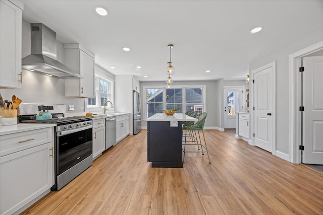 4 Frontrunner Way, Scarborough, ME 04074 - kitchen featuring wall chimney range hood, stainless steel appliances, light wood-type flooring, a kitchen breakfast bar, and a kitchen island