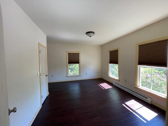 119 Village Rd, Steuben, ME 04680 - unfurnished room with healthy amount of natural light, a baseboard heating unit, and dark wood-style floors
