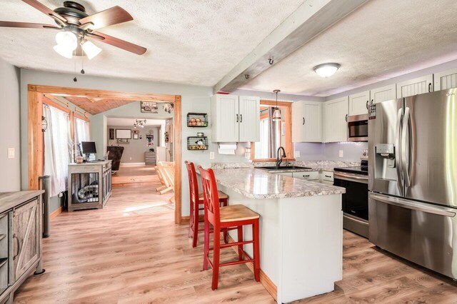 6 Sand Pond Rd, North Berwick, ME 03906 - kitchen featuring stainless steel appliances, a sink, a peninsula, a kitchen bar, and a textured ceiling