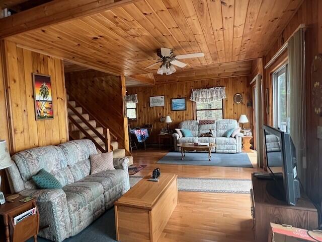 166 Ridge Rd, Frye Island, ME 04071 - living room featuring wooden ceiling, wooden walls, a ceiling fan, wood finished floors, and stairway