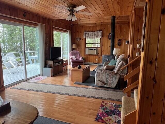 166 Ridge Rd, Frye Island, ME 04071 - living room with a wood stove, a baseboard heating unit, cooling unit, wood ceiling, and wooden walls