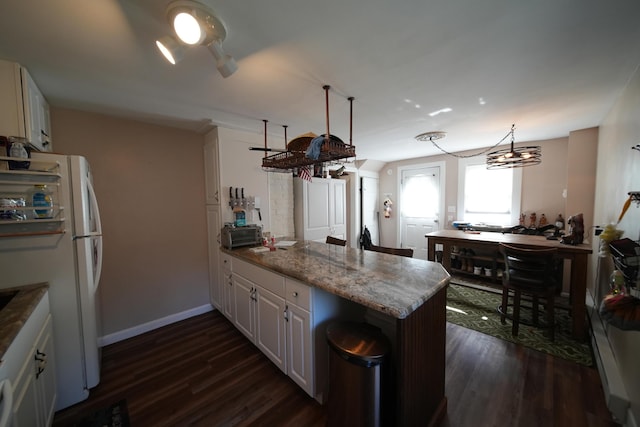 29 Columbia St, Houlton, ME 04730 - kitchen featuring freestanding refrigerator, dark wood-style floors, a peninsula, and white cabinetry