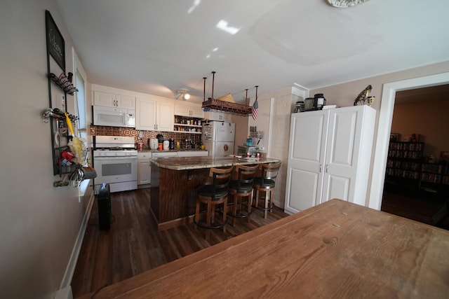 29 Columbia St, Houlton, ME 04730 - kitchen with white appliances, dark wood-style flooring, a peninsula, a kitchen breakfast bar, and tasteful backsplash