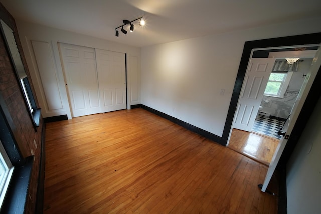 29 Columbia St, Houlton, ME 04730 - unfurnished bedroom featuring hardwood / wood-style floors, a chandelier, a closet, track lighting, and baseboards
