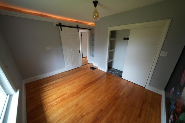 29 Columbia St, Houlton, ME 04730 - unfurnished bedroom with a barn door, light wood finished floors, and baseboards