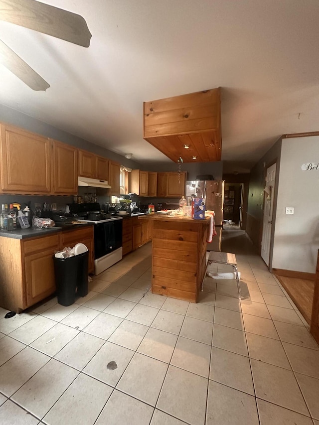 187 Purkis Rd, Buckfield, ME 04220 - kitchen with range with electric stovetop, freestanding refrigerator, under cabinet range hood, light tile patterned floors, and dark countertops