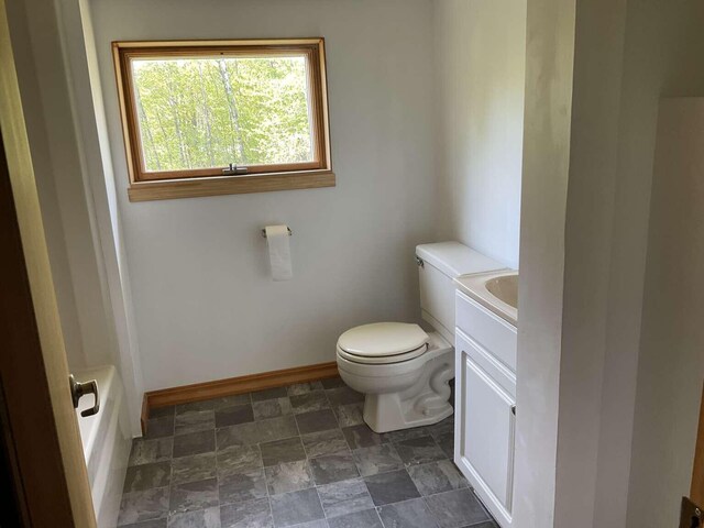 264 Watson Hill Rd, Limerick, ME 04048 - bathroom with toilet, baseboards, vanity, a bathtub, and stone finish floors
