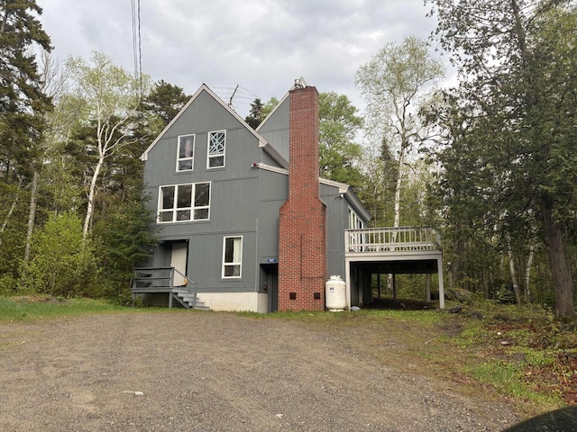 2011 Clark St, Carrabassett Valley, ME 04947 - rear view of house featuring a chimney, a wooden deck, and dirt driveway