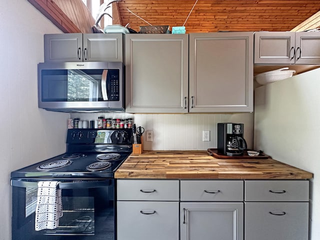 144 Sinclair Rd, Sinclair, ME 04779 - kitchen featuring black electric range, stainless steel microwave, butcher block countertops, wooden walls, and gray cabinets